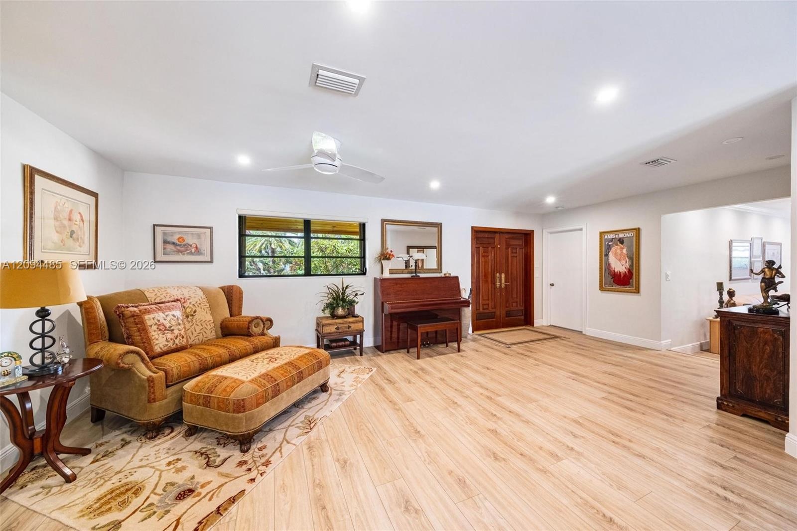 Open-concept living space featuring wood-finish flooring, recessed lighting, a ceiling fan, and double wood-paneled entry doors