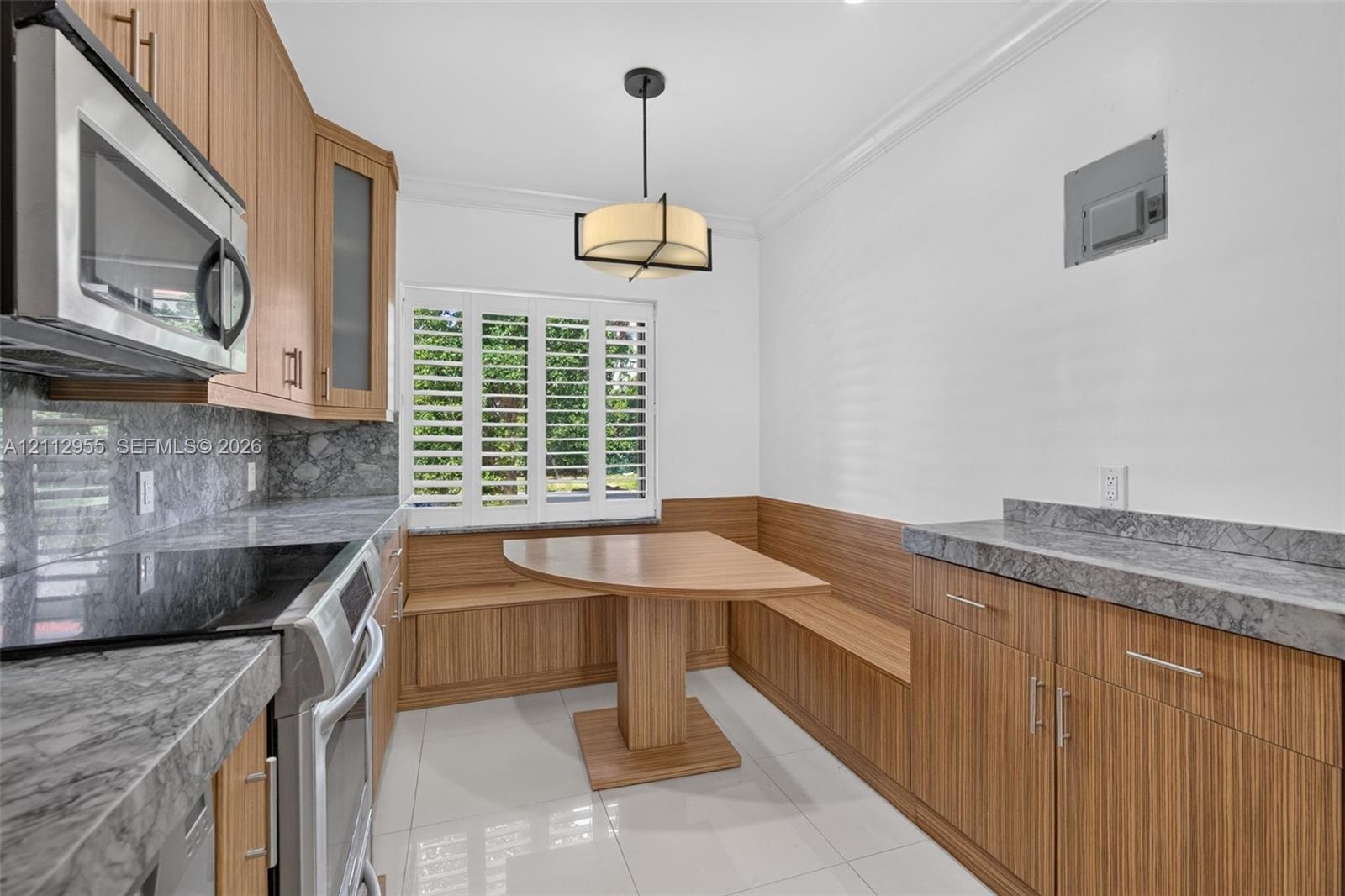 Kitchen featuring wood-finish cabinetry, stone-surface countertops, built-in breakfast nook with integrated bench seating, polished tile flooring, and