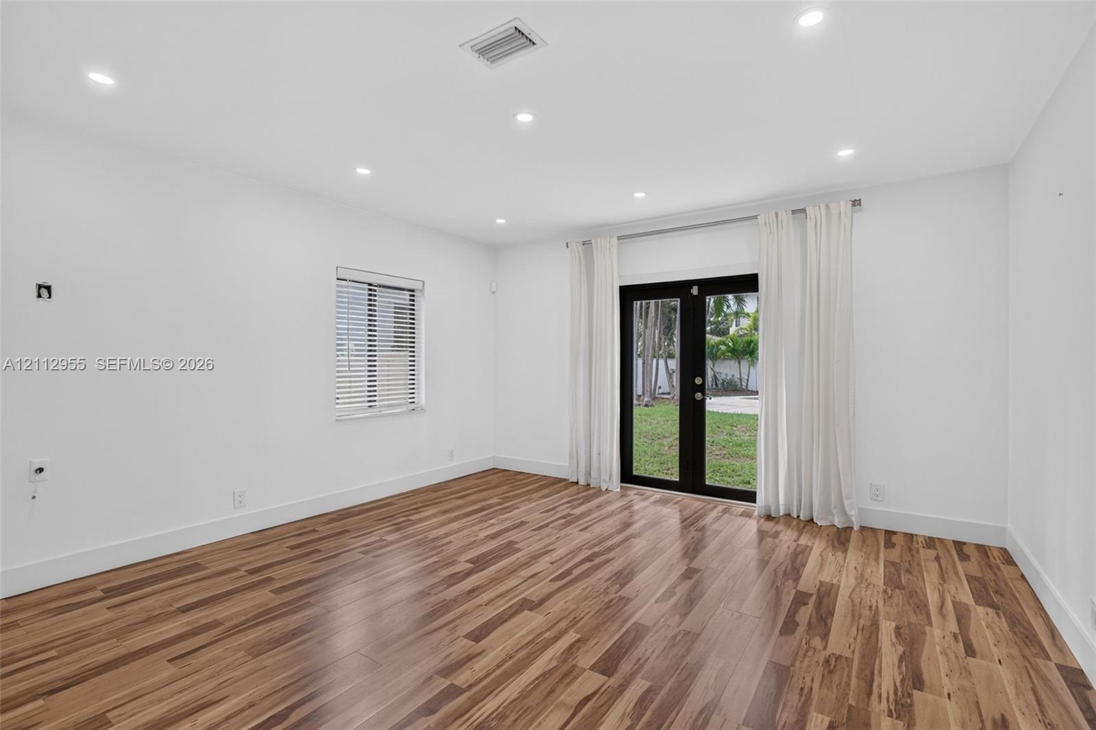 Interior space featuring wood-finish flooring, recessed lighting, and black-framed double glass doors providing an exterior perspective