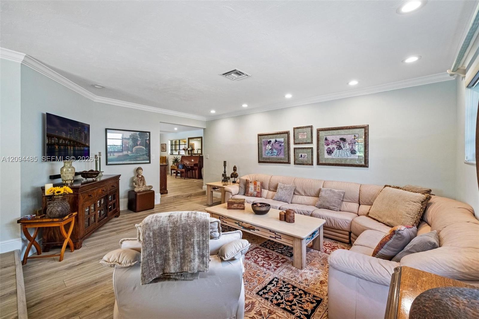 Living area featuring wood-finish flooring, recessed lighting, and crown molding