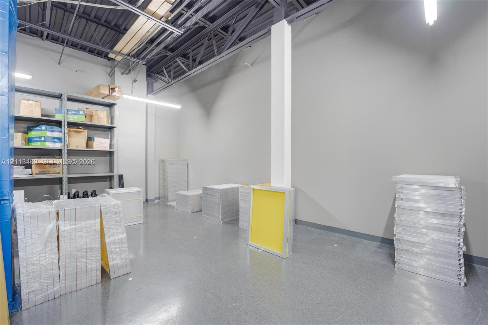 Industrial-style interior featuring high, exposed-truss ceilings, durable epoxy-finish flooring, and built-in metal industrial shelving
