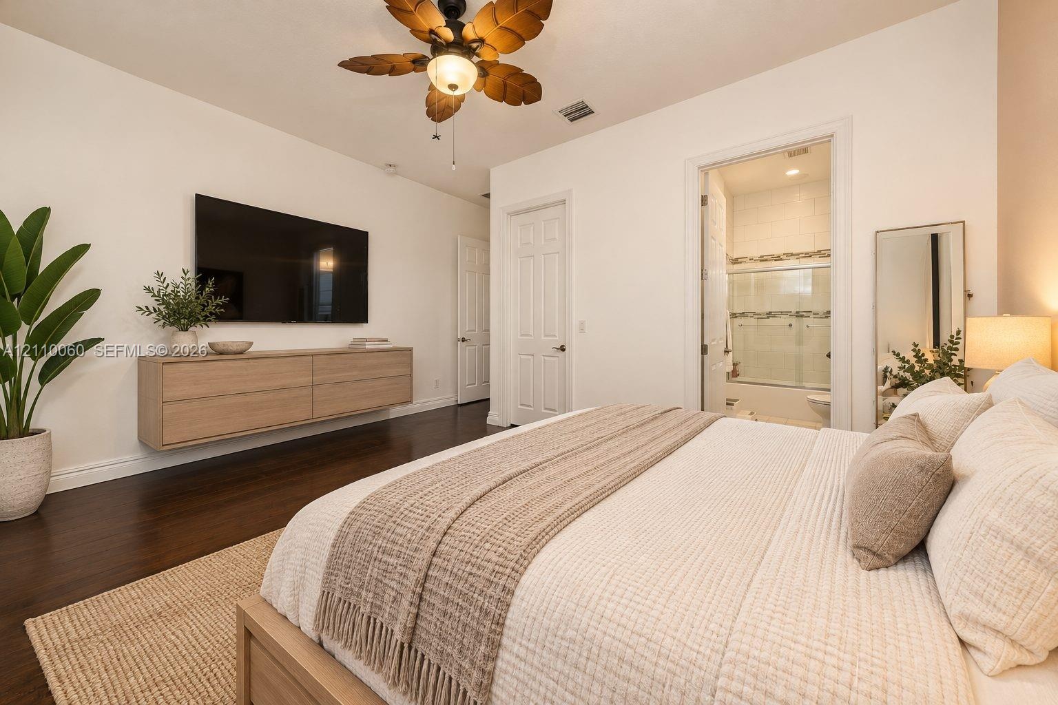 Virtually staged. Dark wood-finish flooring, wall-mounted light-toned cabinetry, and a ceiling fan with leaf-shaped blades
