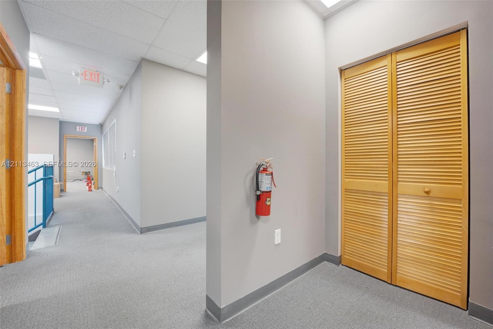Interior hall featuring neutral-toned carpeting, drop ceiling with recessed lighting, and a bi-fold wooden closet door