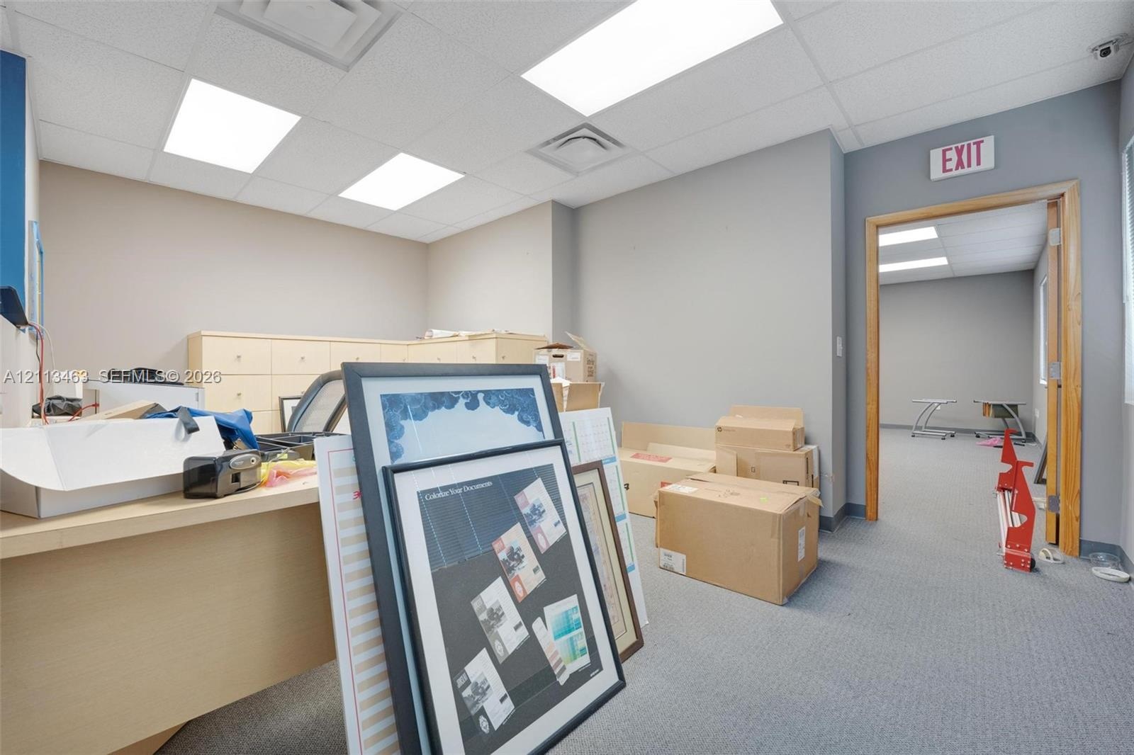 Interior space featuring light-toned built-in cabinetry, grey carpeted flooring, and recessed ceiling lighting