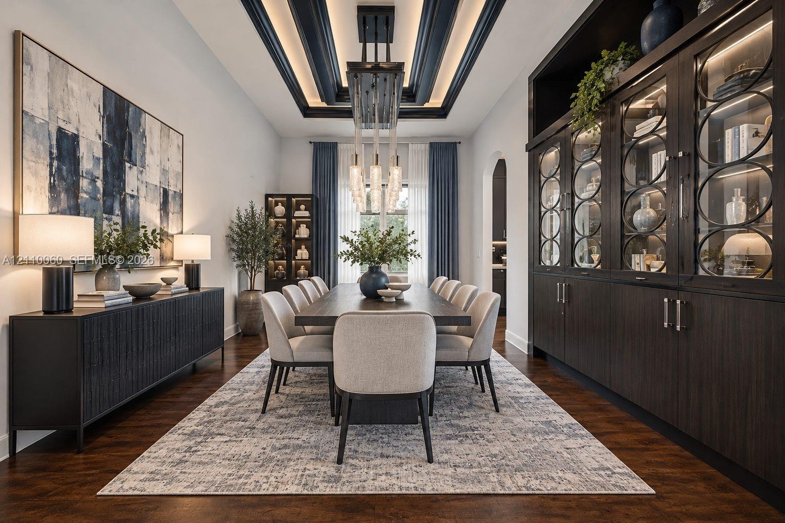 Virtually staged. Formal dining area featuring a tray ceiling with recessed lighting, custom floor-to-ceiling built-in cabinetry with glass-paneled di