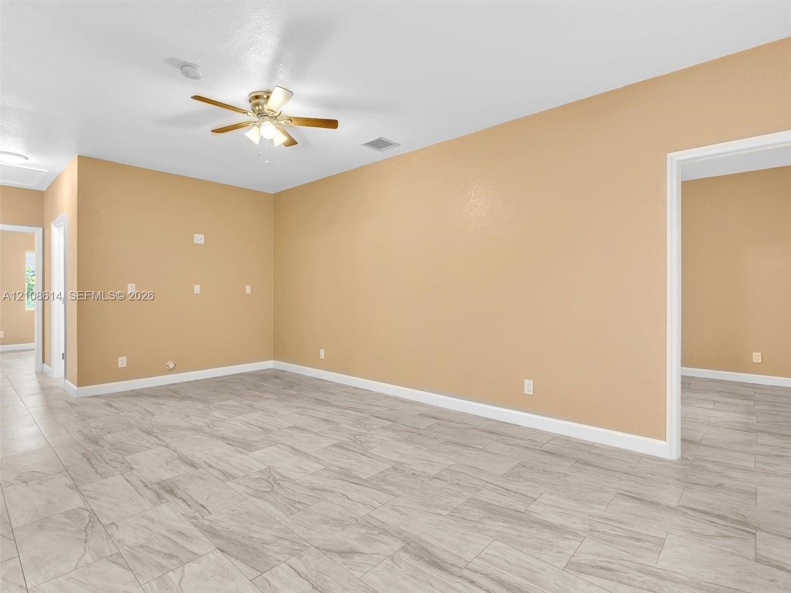 Spacious interior featuring large-format tile flooring and a ceiling-mounted light fixture with a fan