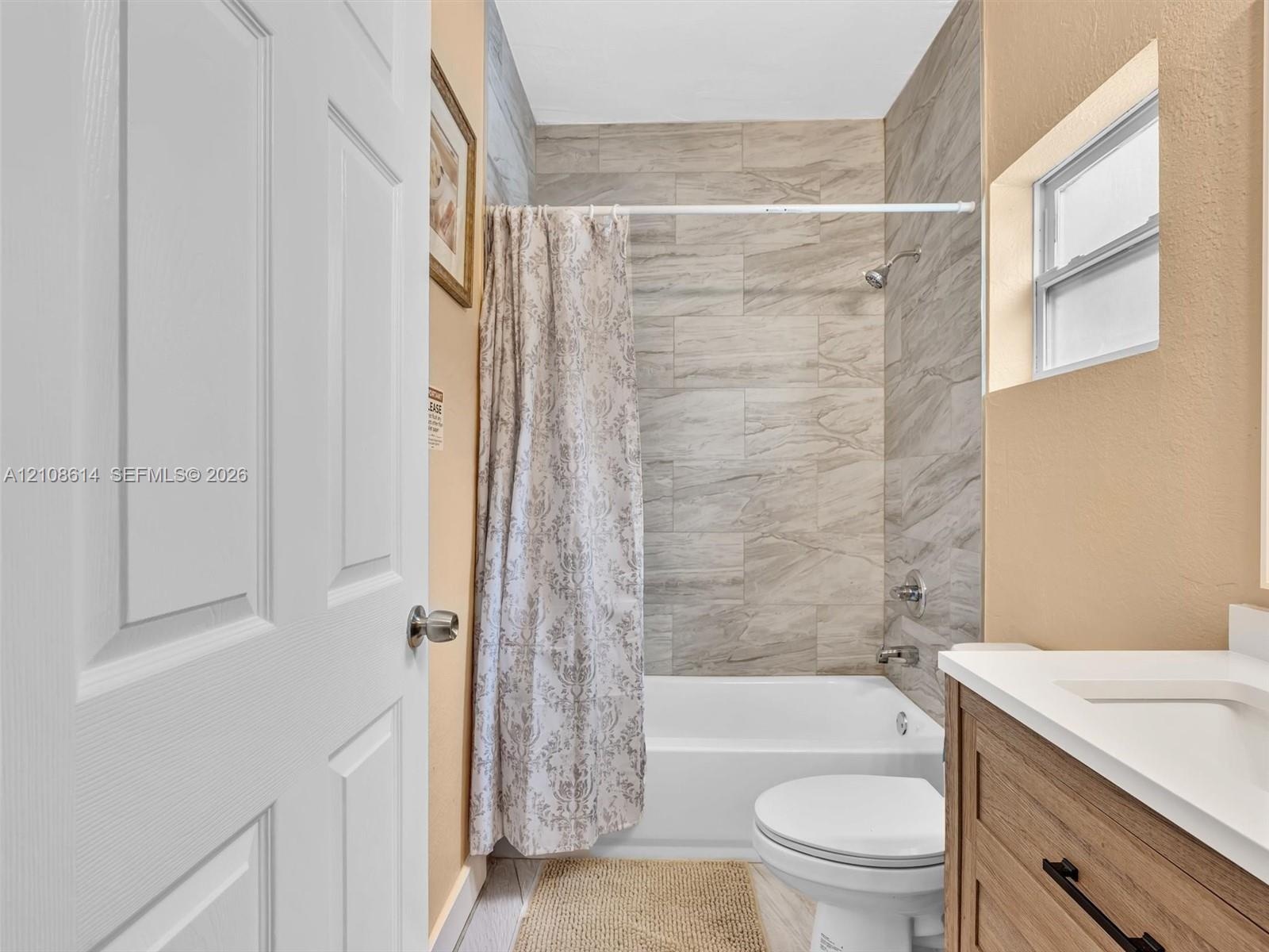 Bathroom featuring a vanity with a light wood-finish cabinet, white countertop, integrated sink, and polished chrome fixtures, accented by neutral-ton