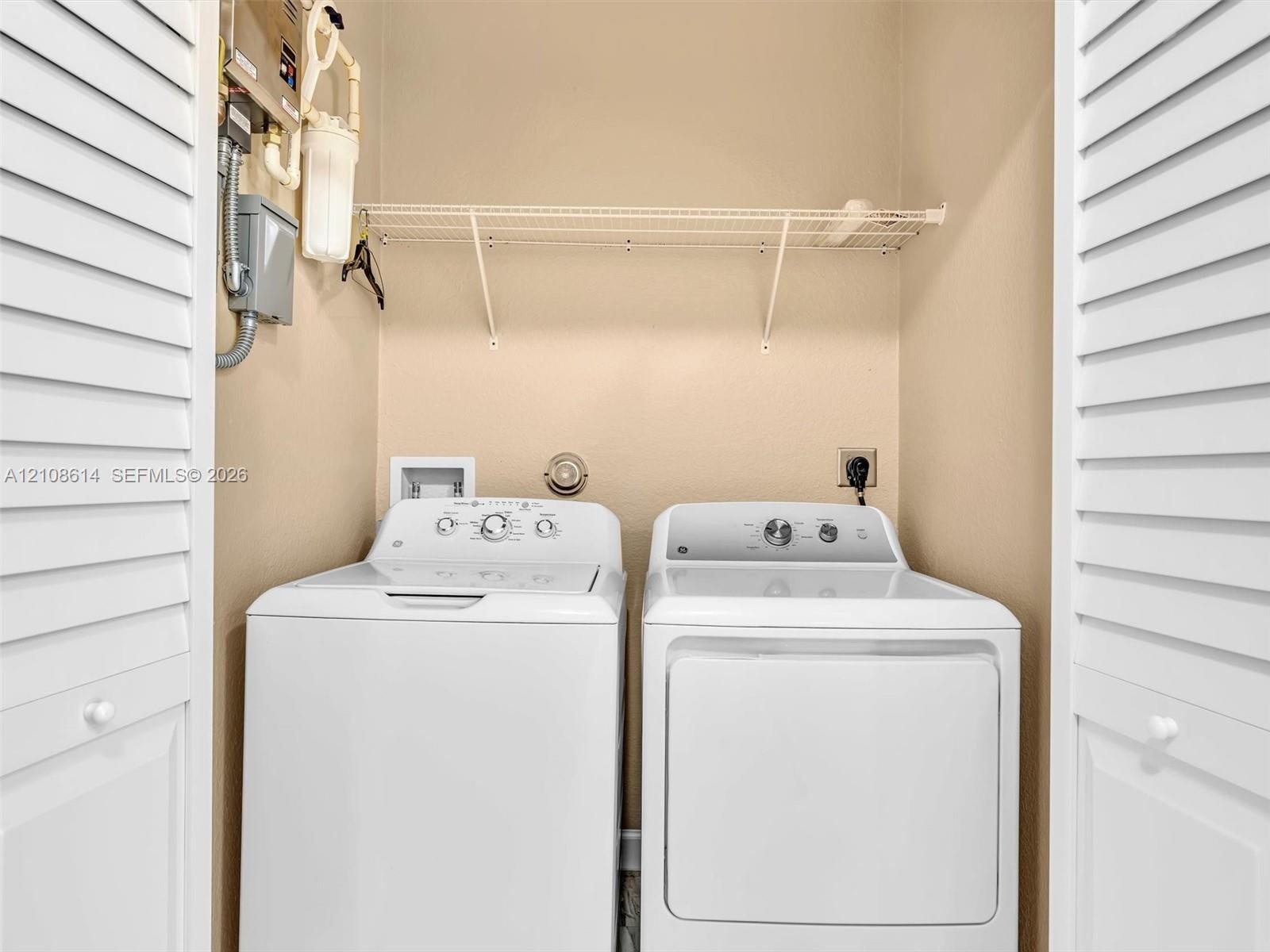 Laundry area featuring louvered bifold doors and built-in wire shelving