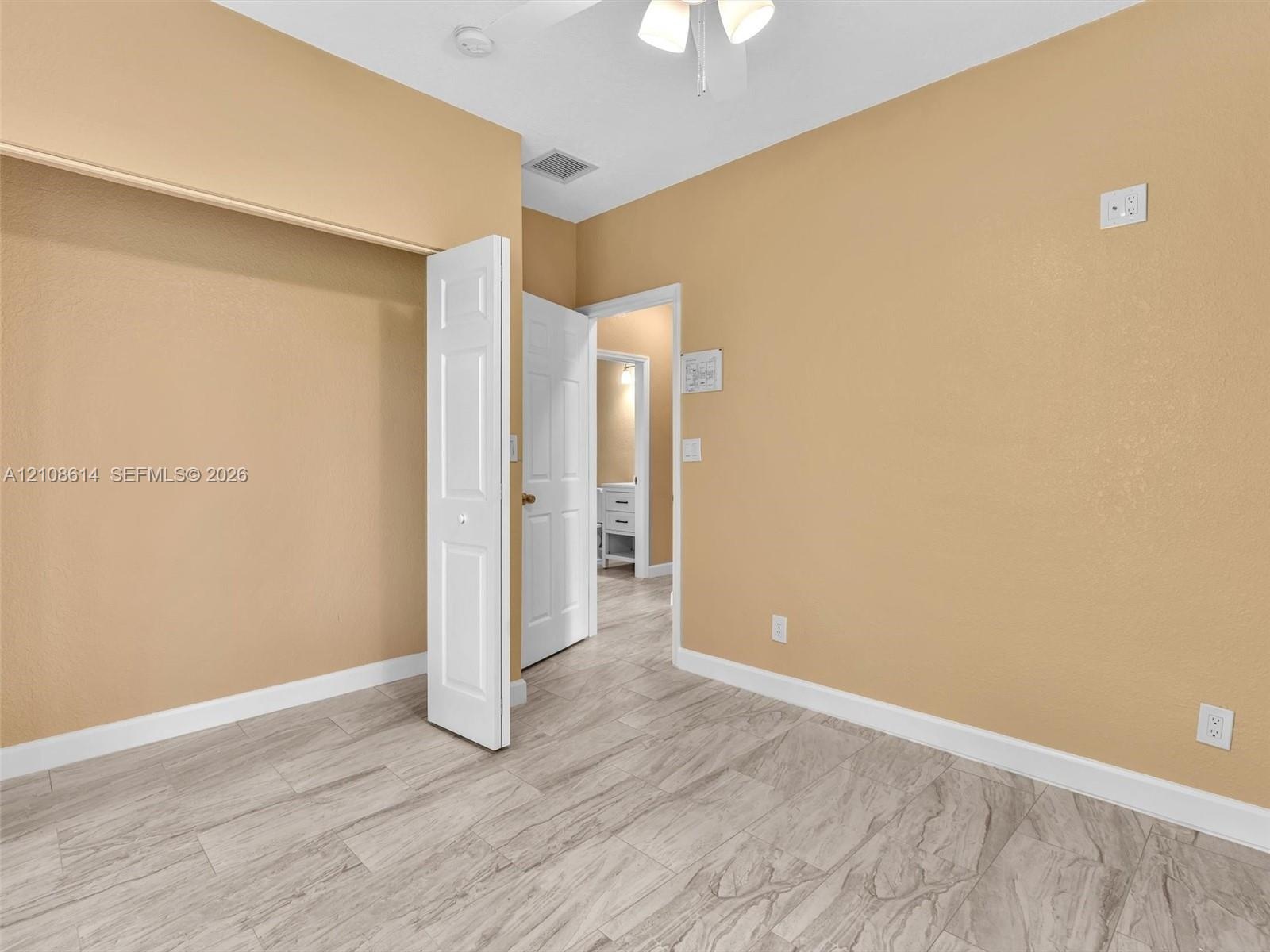 Neutral-toned interior space featuring light-colored wood-finish flooring, a bi-fold closet door, and a ceiling-mounted light fixture