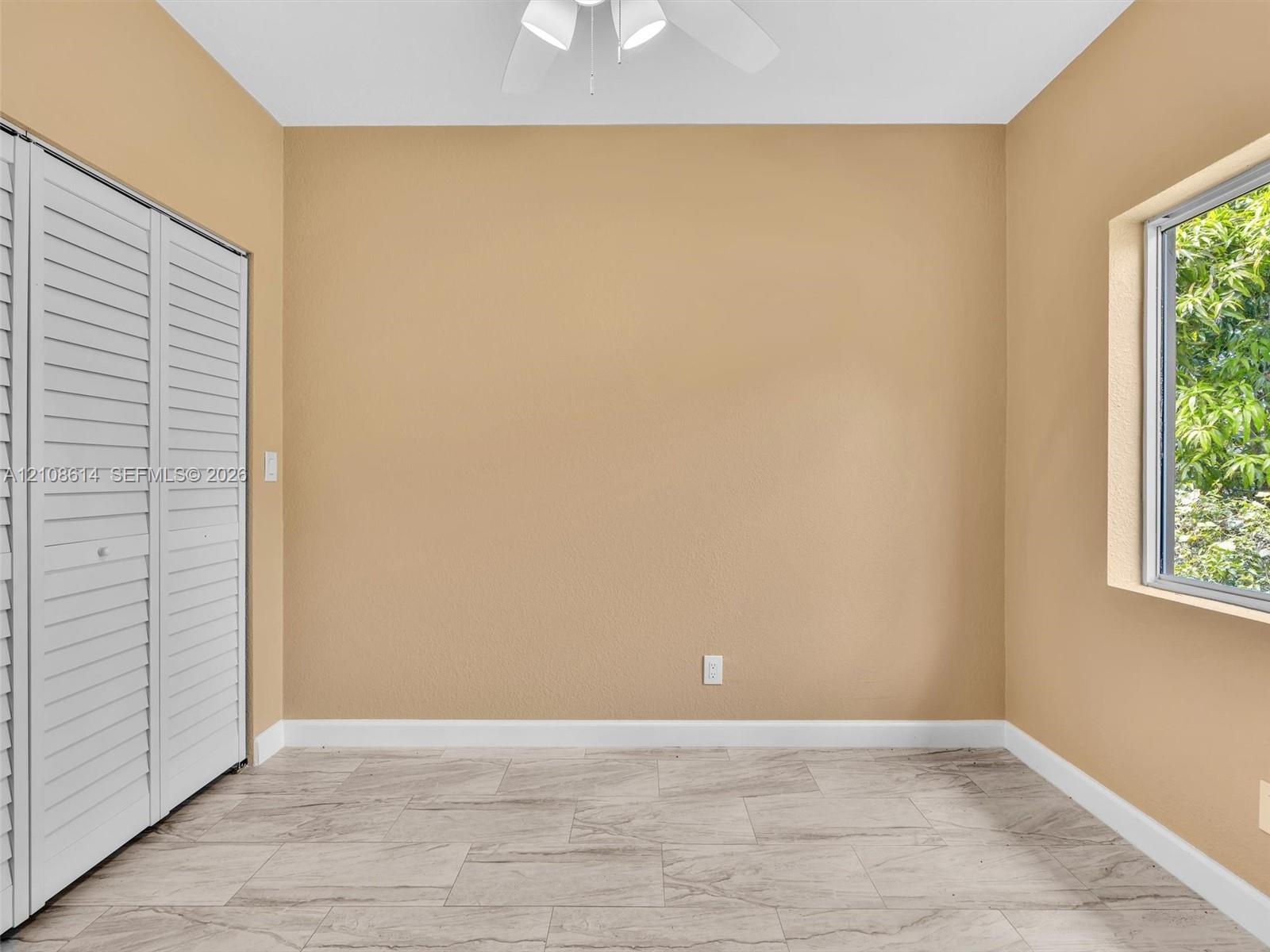 Tile flooring with a stone-finish pattern, bi-fold closet doors, and a ceiling-mounted light fixture