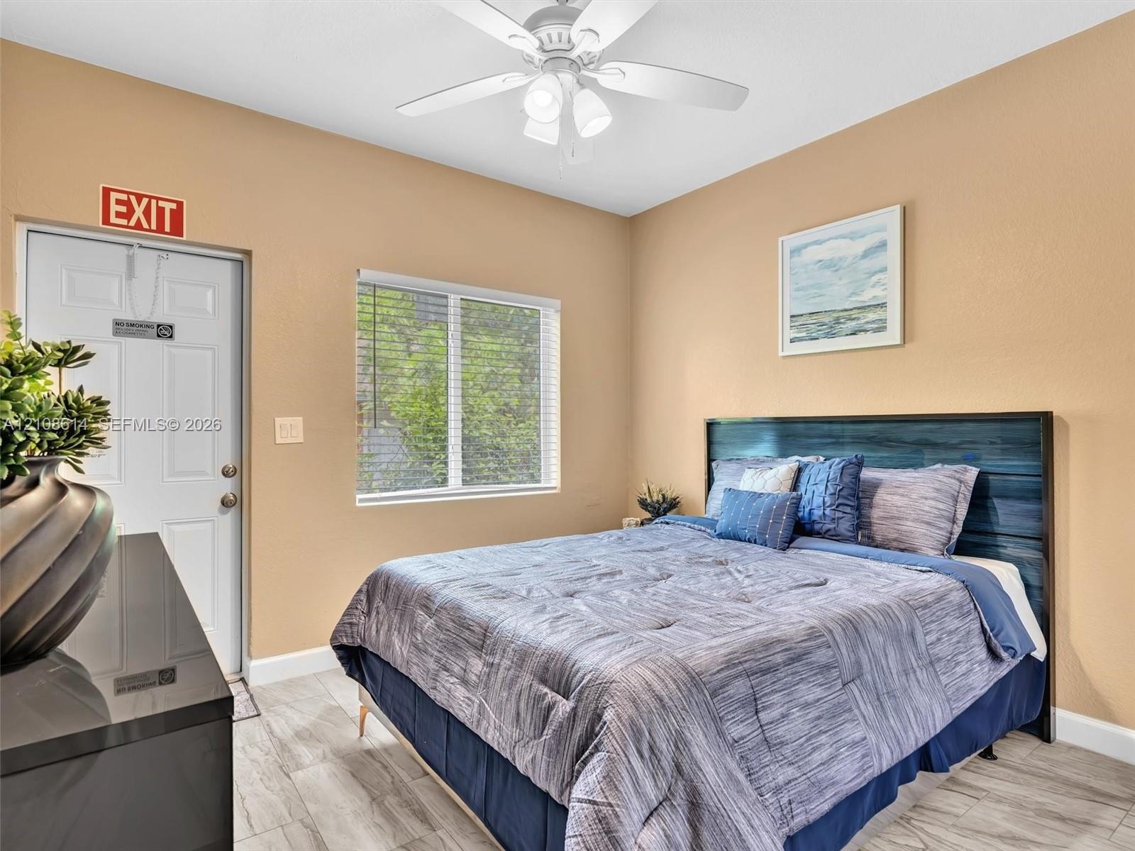 Neutral-toned interior featuring wood-finish tile flooring, a multi-pane window, and a ceiling-mounted light fixture with a fan