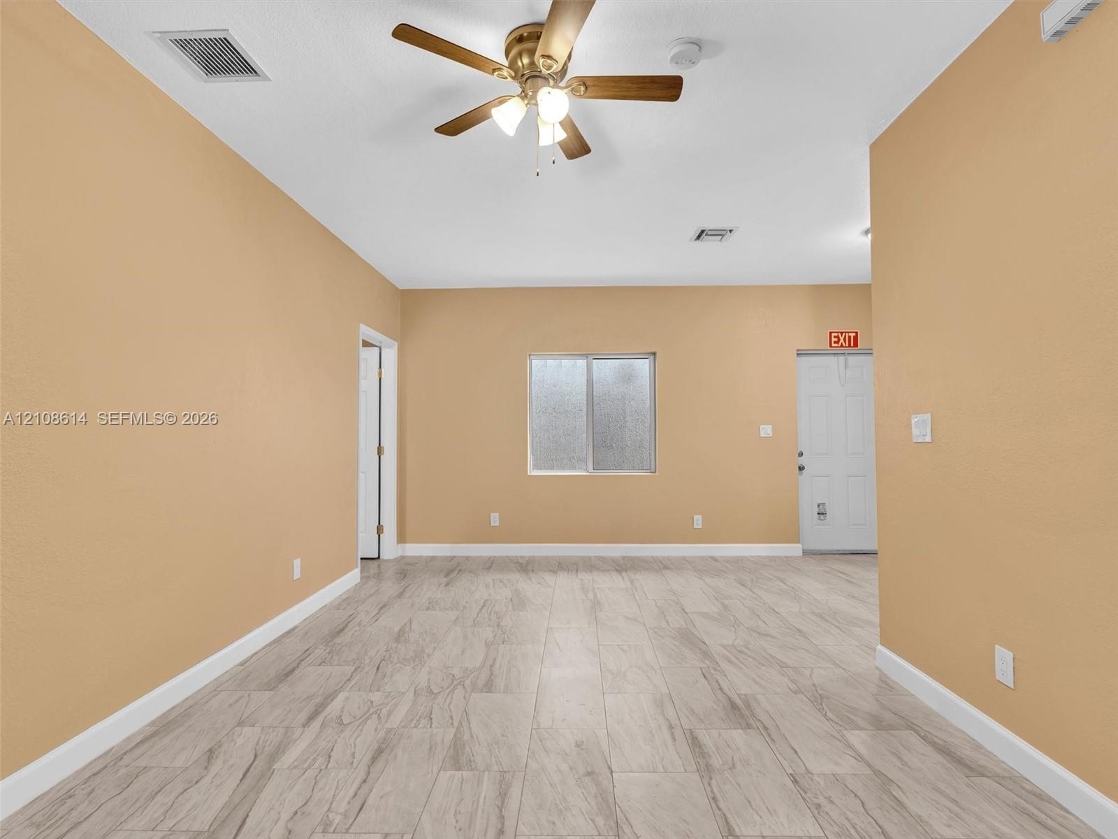 Interior space featuring wood-finish tile flooring, a neutral wall palette, a multi-blade ceiling fan with integrated lighting, and a single sliding w
