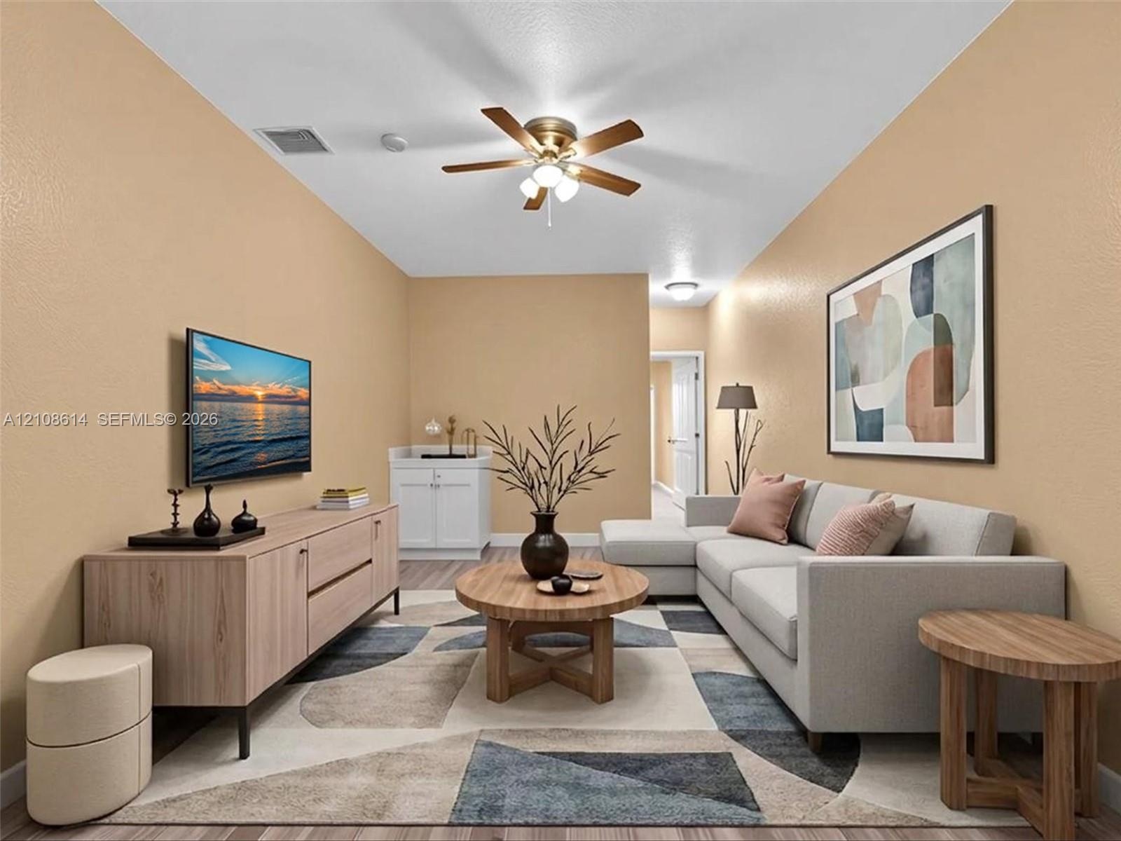 Living area featuring wood-finish flooring, a ceiling fan with integrated lighting, and built-in cabinetry