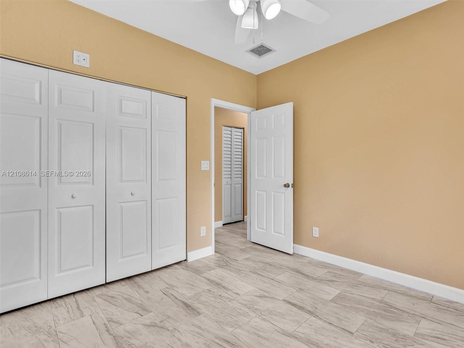 Interior room featuring stone-finish tile flooring, multi-panel closet doors, six-panel interior doors, and a ceiling-mounted light fixture