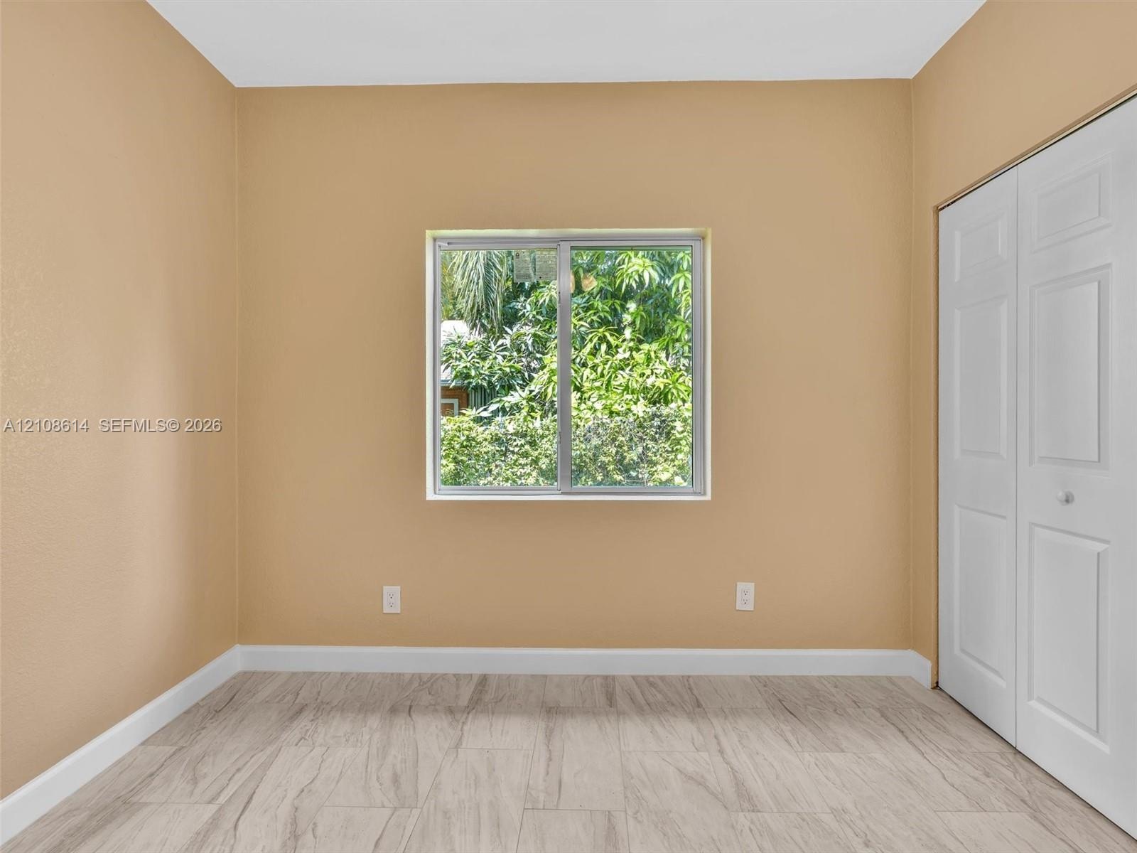 Room featuring neutral-toned walls, wood-finish flooring, a sliding window, and a built-in closet with paneled doors