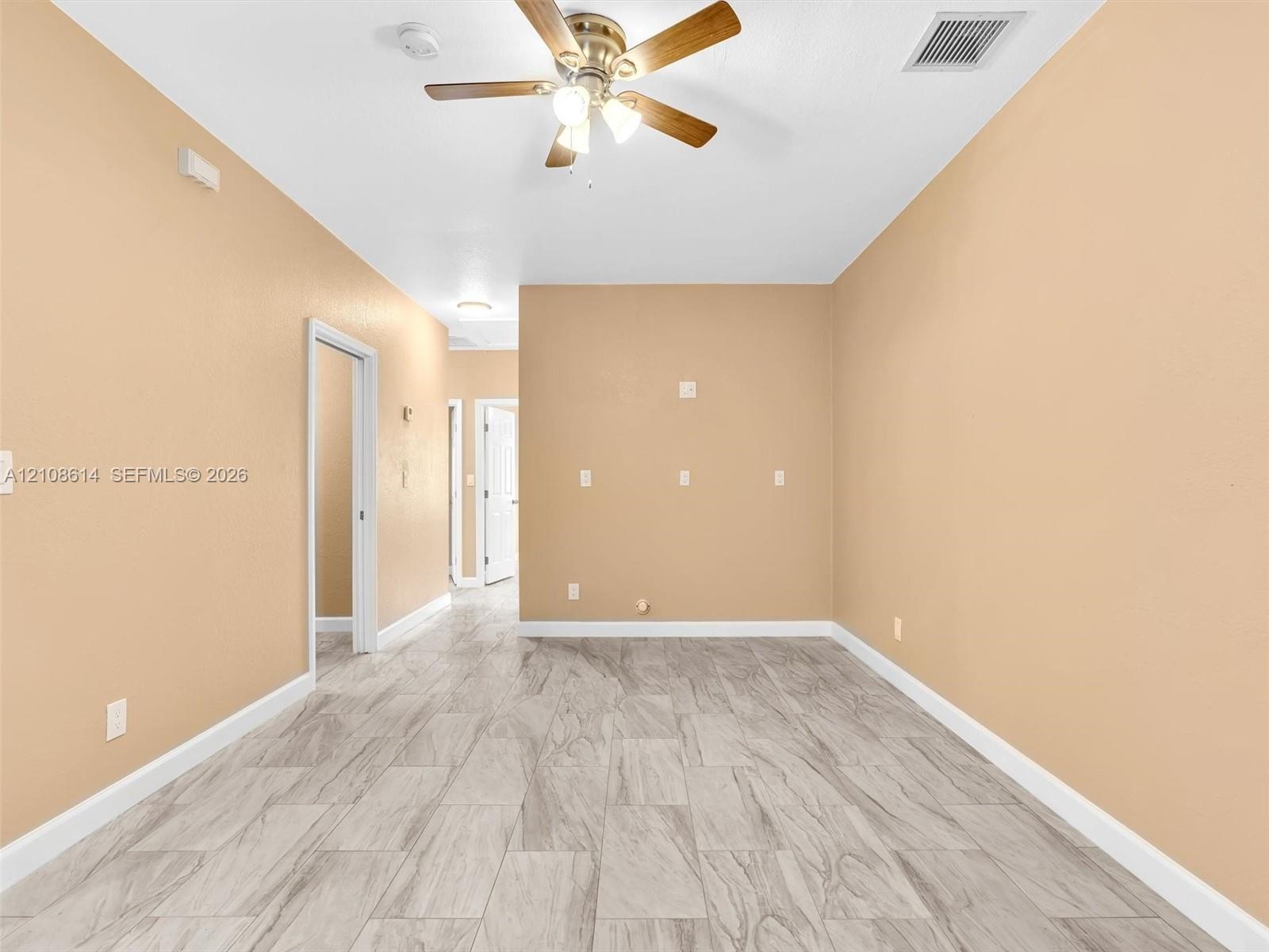 Interior space featuring wood-finish flooring, neutral wall tones, and a ceiling fan with integrated light fixtures