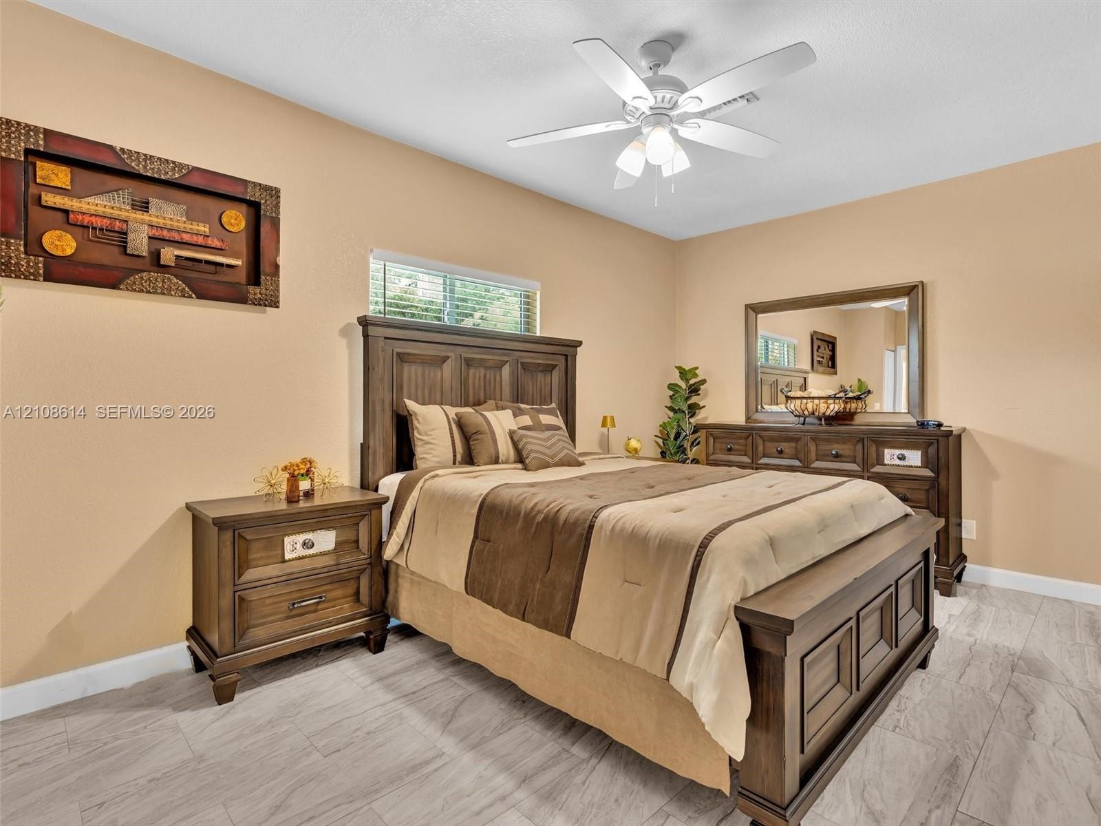 Tile flooring with a wood-finish, neutral wall paint, and a central ceiling fan with integrated lighting