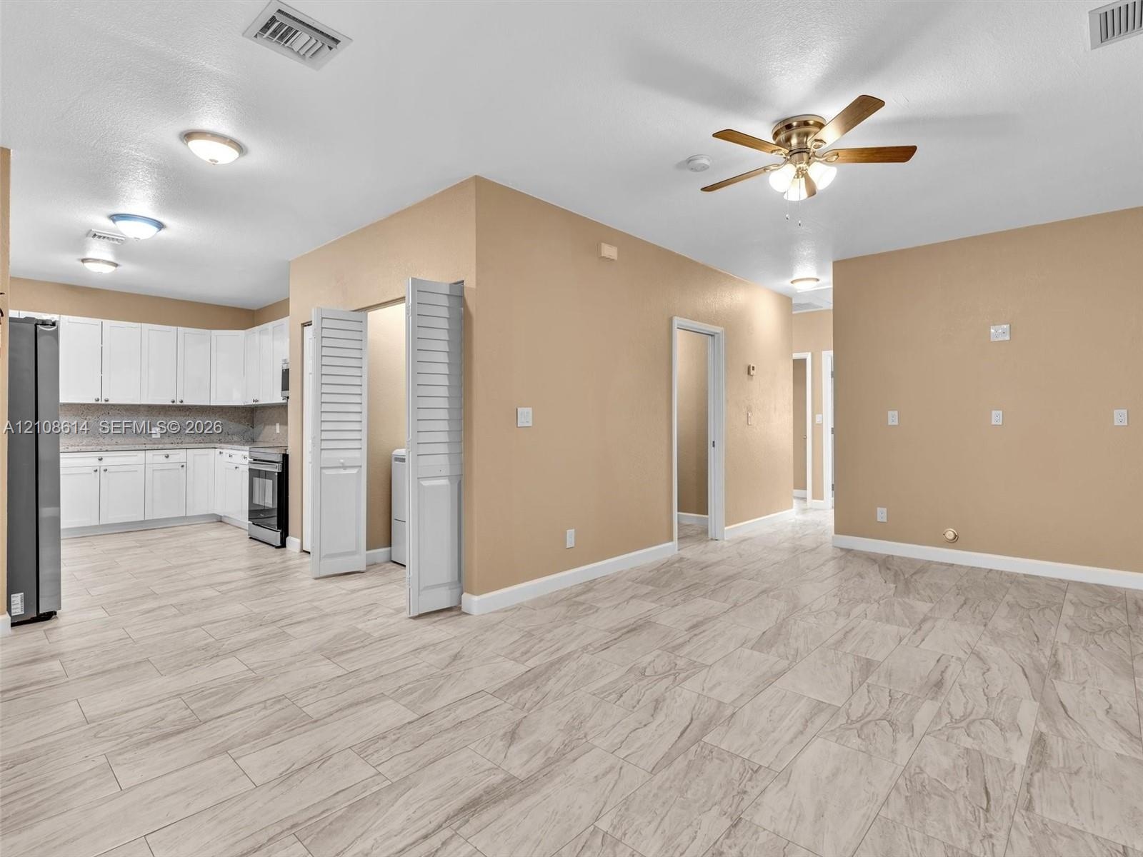Kitchen featuring white cabinetry, stone-finish countertops, and stainless steel appliances, complemented by wood-finish flooring and a ceiling fan