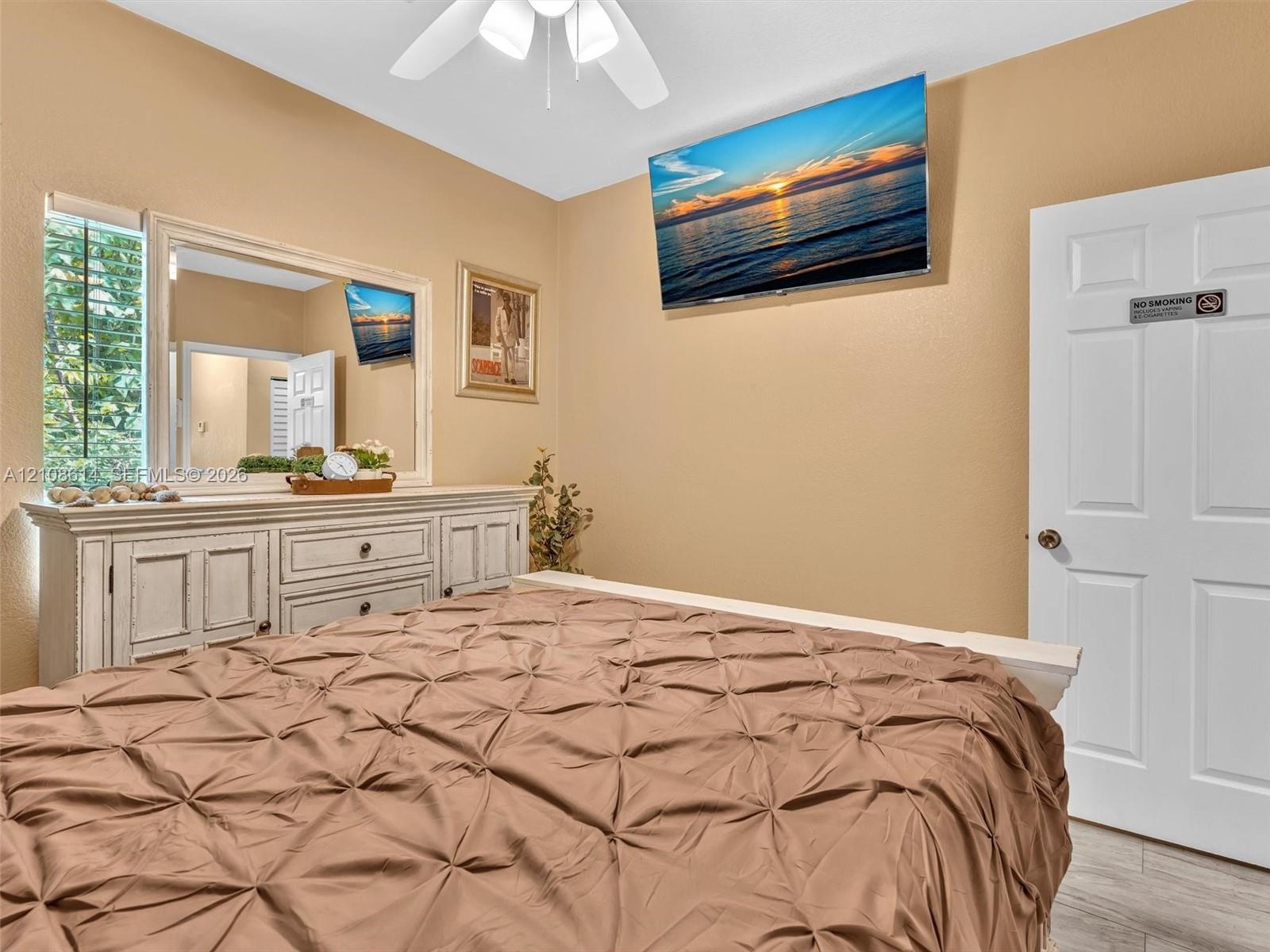Neutral wall palette, ceiling-mounted paddle fan with integrated lighting, four-panel interior door, and light-toned wood-finish flooring