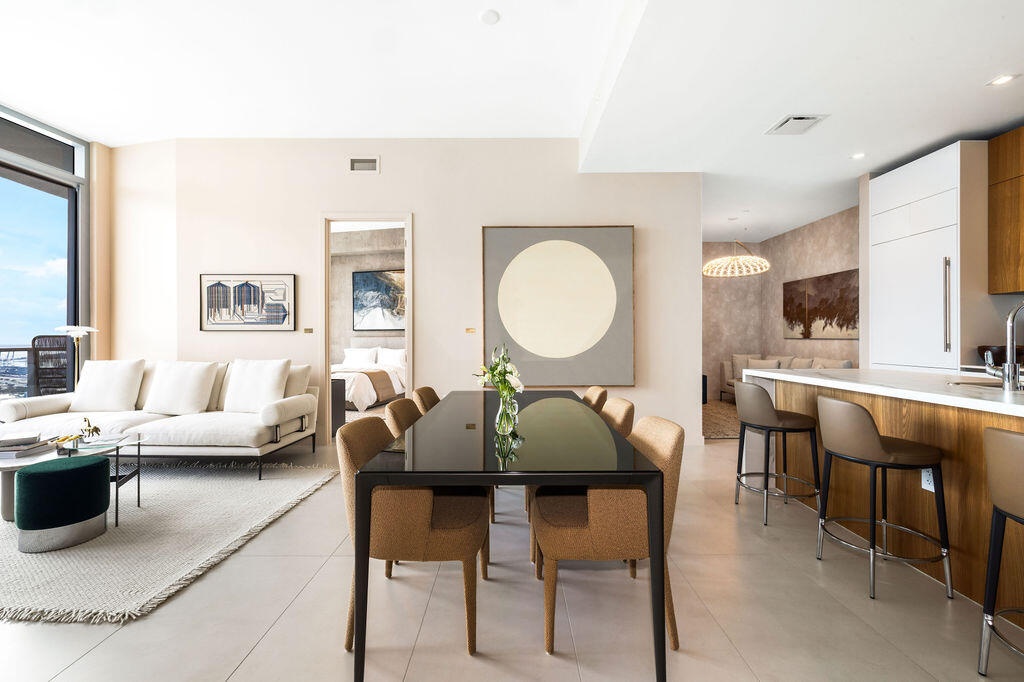 Open-concept interior featuring large-format tile flooring, floor-to-ceiling windows, and a kitchen island with wood-veneer cabinetry and a solid-surf
