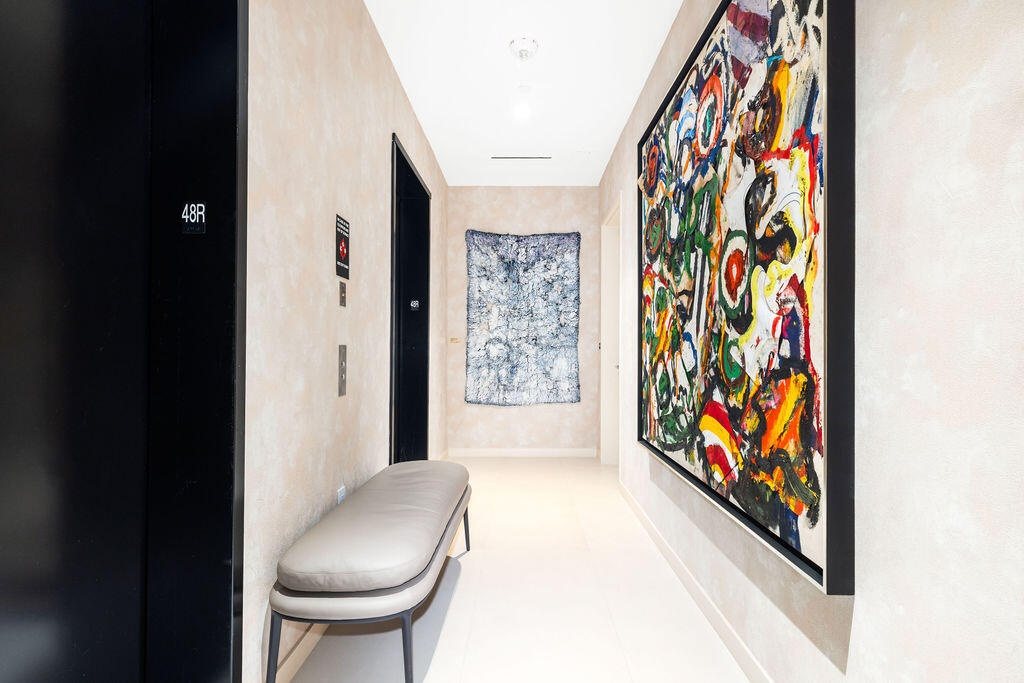 Hallway featuring smooth textured wall finishes, solid-core black paneled doors, and polished stone flooring
