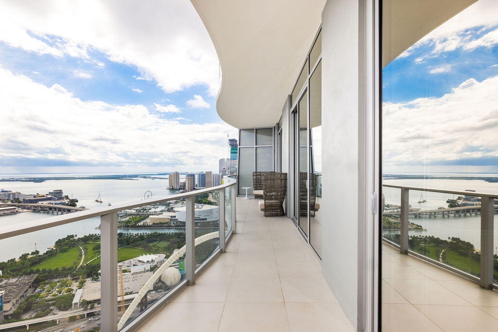 Curved balcony featuring tile flooring, full-height glass sliding doors, and a metal railing with glass panels