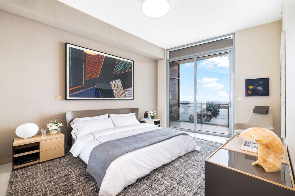 Full-height sliding glass doors with access to a private balcony, neutral wall finishes, and overhead recessed lighting