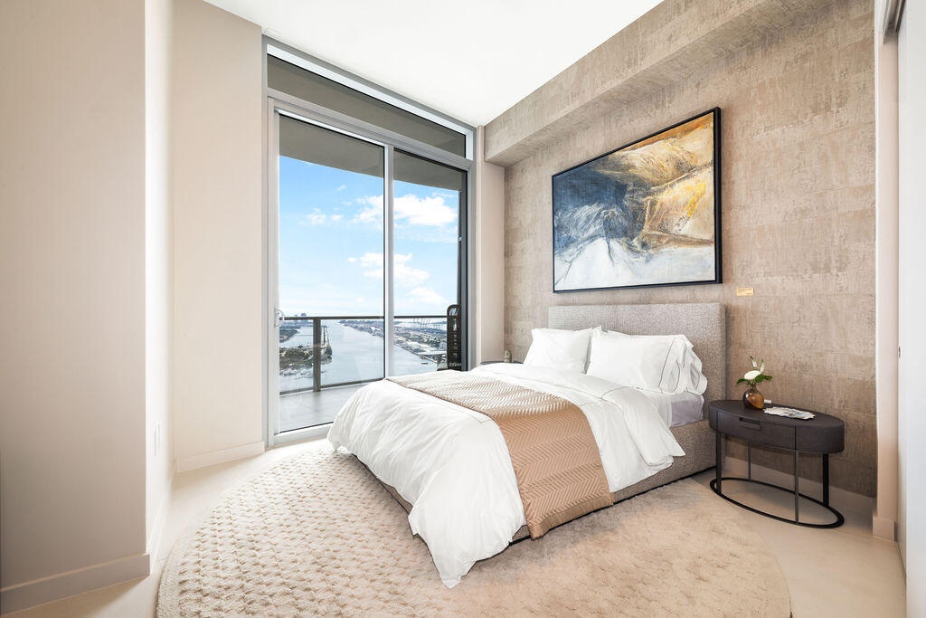 Floor-to-ceiling glass sliding door, large private balcony, textured stone feature wall, and neutral polished flooring