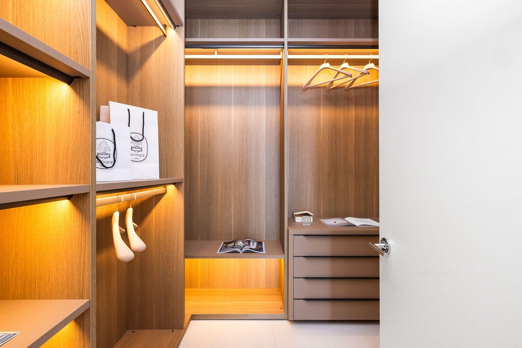 Custom walk-in closet featuring wood-finish cabinetry, built-in shelving, integrated lighting, and a multi-drawer storage unit