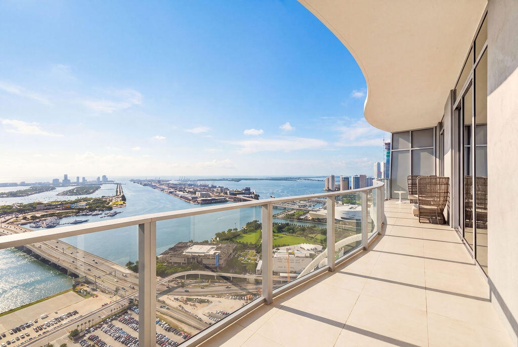Curved, expansive balcony featuring large-format tile flooring and a glass panel railing