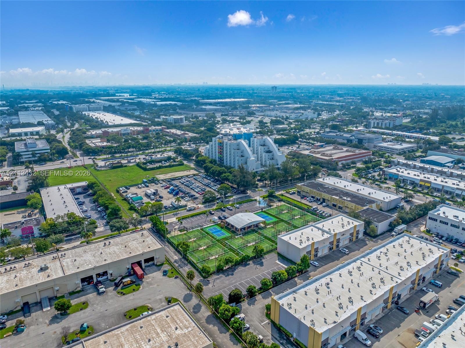Aerial perspective of commercial complex, paved parking areas, and surrounding professional buildings