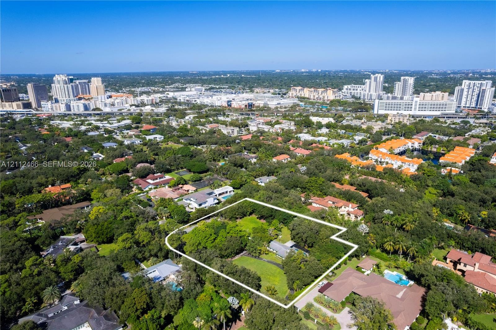 Aerial perspective featuring a large, irregularly shaped lot with mature trees and expansive green space