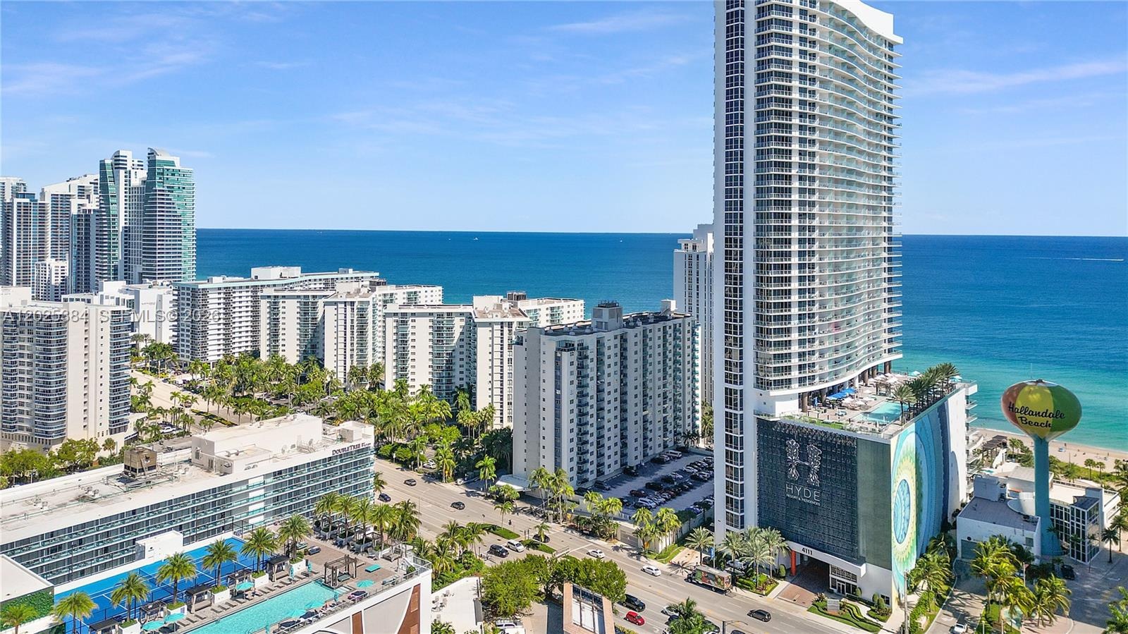 High-rise architectural structure with floor-to-ceiling glass windows, integrated rooftop pool, and coastal shoreline exposure