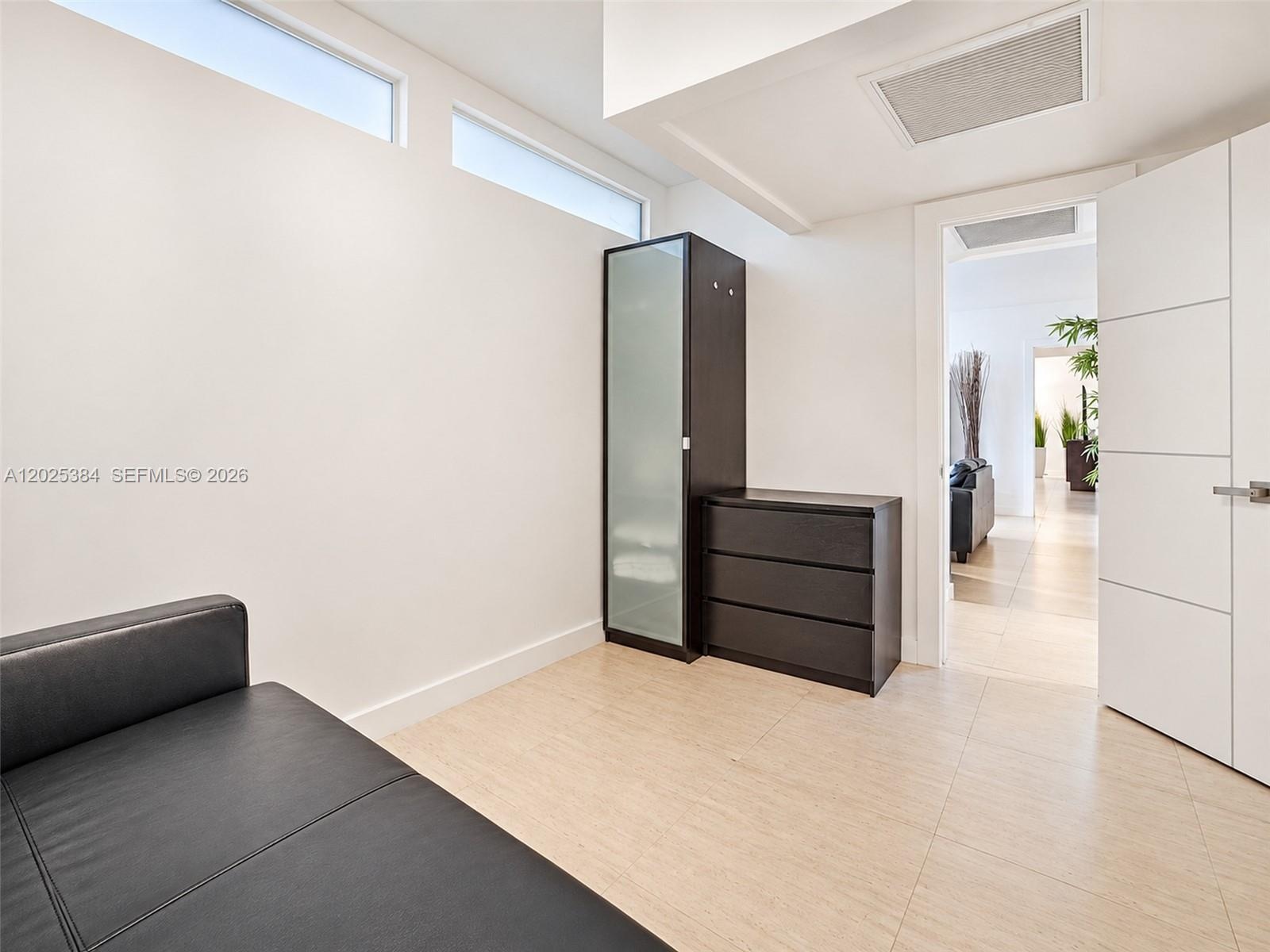 Interior space featuring clerestory windows, neutral tile flooring, and a multi-panel interior door