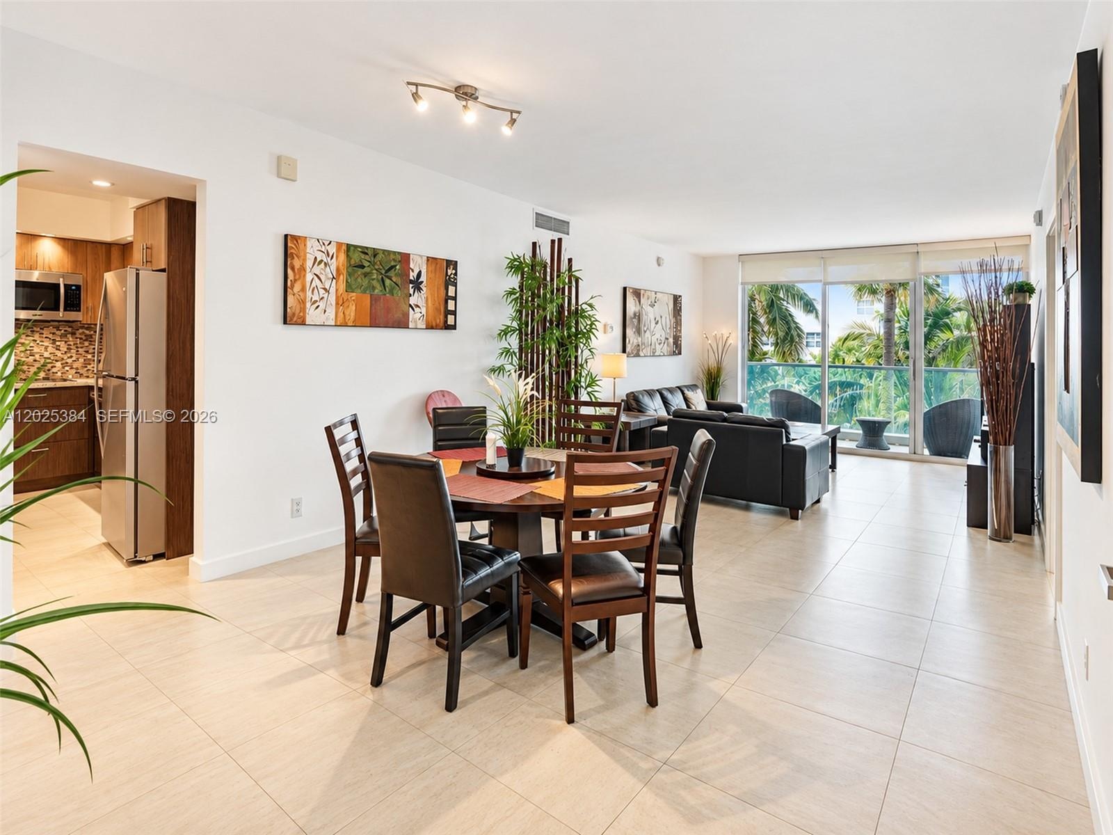Open-concept living space featuring large-format tile flooring, floor-to-ceiling sliding glass doors, and a kitchen equipped with stainless steel appl