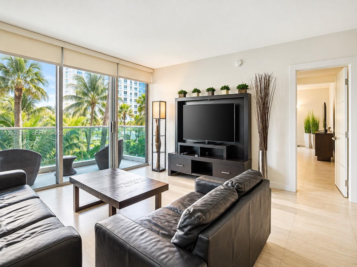 Floor-to-ceiling sliding glass doors, balcony with glass railing, and large-format tile flooring