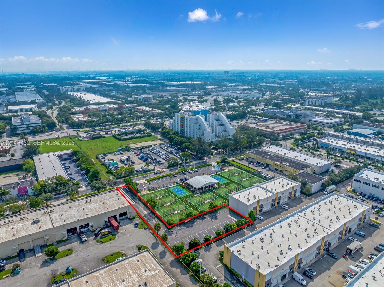 Aerial perspective of the subject parcel featuring a dedicated asphalt parking area, integrated surface-level parking rows, and boundary landscaping