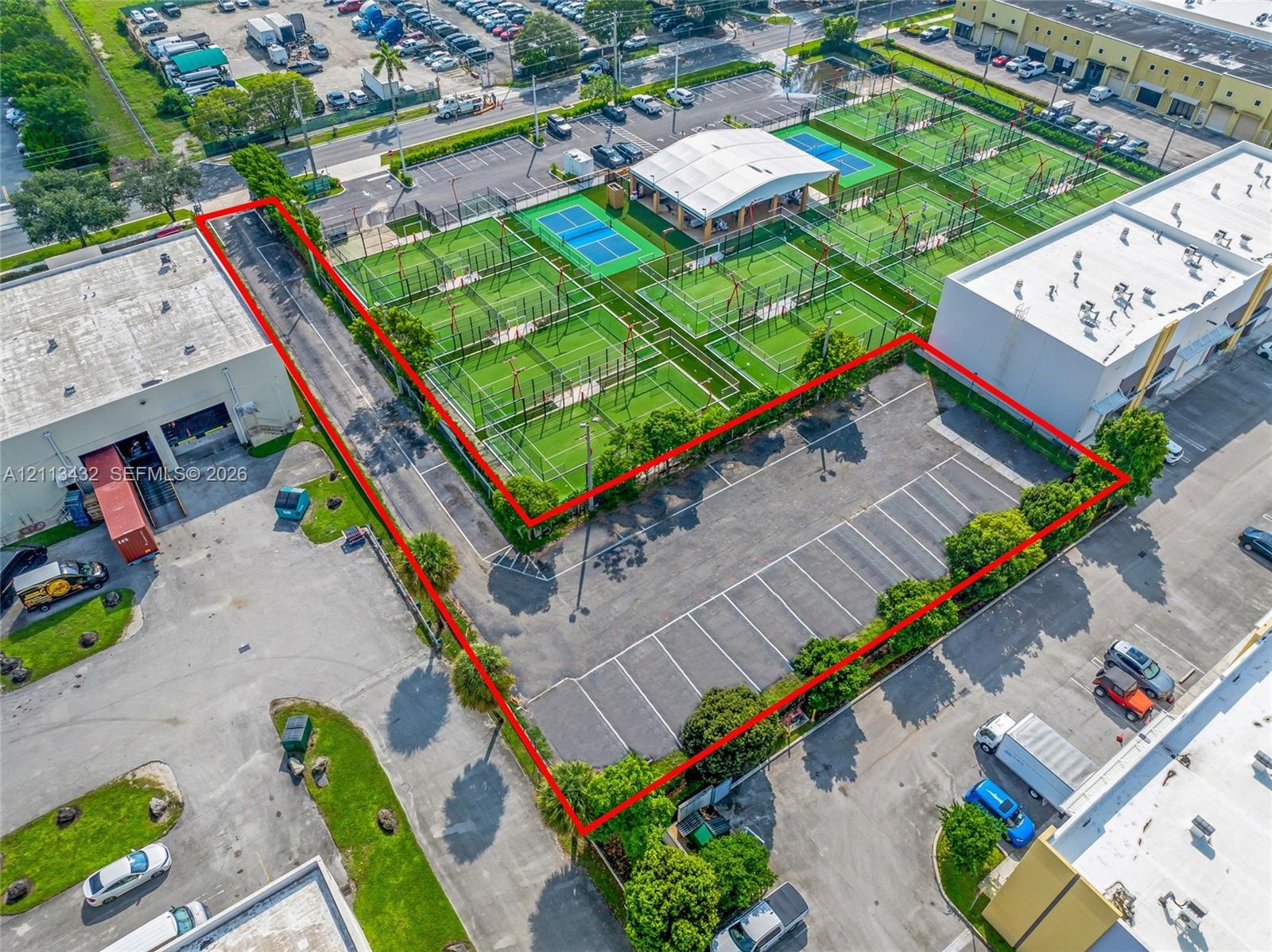 Asphalt-paved surface parking lot featuring designated stall markings, perimeter landscaping with mature trees.