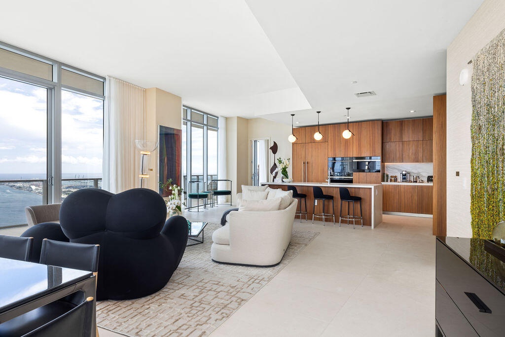Floor-to-ceiling windows, custom wood-finish cabinetry, built-in panel-ready appliances, stone-topped kitchen island, and large-format tile flooring