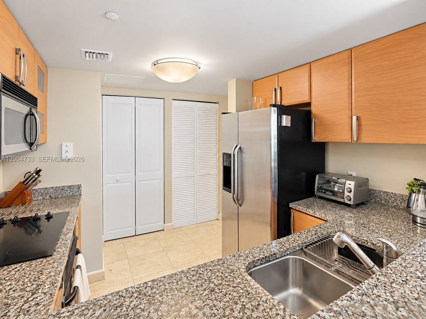 Kitchen featuring light-finish cabinetry, stone countertops, stainless steel appliances, dual-basin stainless steel sink, and tile flooring