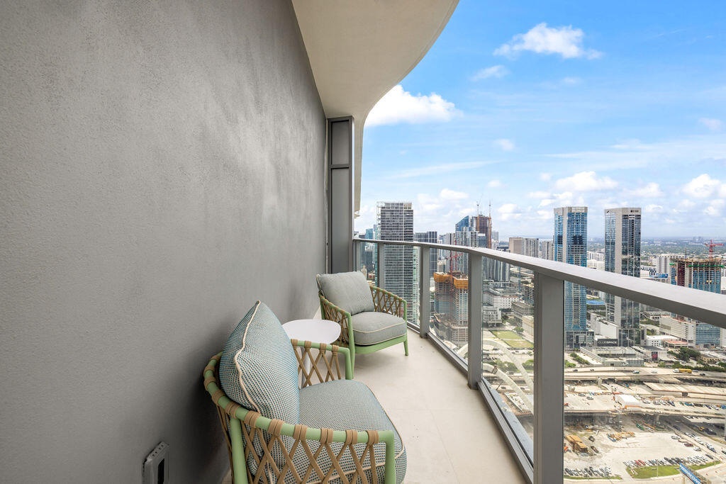 Covered balcony featuring a concrete floor, a solid exterior wall, and a metal railing with glass panels
