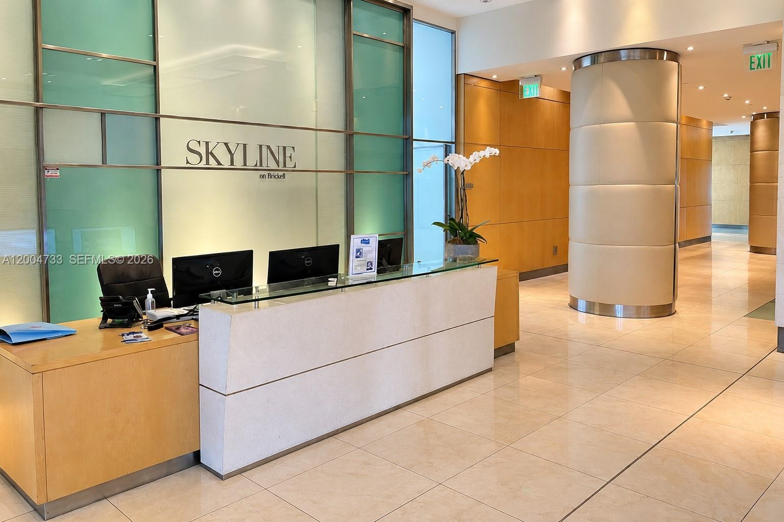 Reception area featuring stone-finish flooring, wood-paneled walls, a built-in stone-top reception desk, and a prominent cylindrical structural column