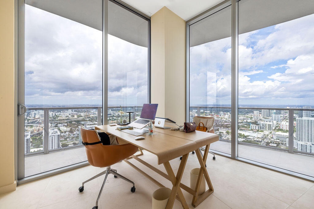 Floor-to-ceiling windows, wrap-around glazing, light-toned tile flooring, and a glass-enclosed balcony