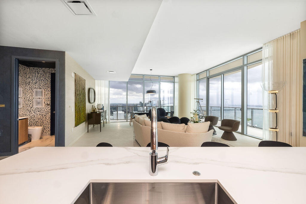 Kitchen featuring a stone-surface island, stainless steel undermount sink, and chrome high-arc faucet