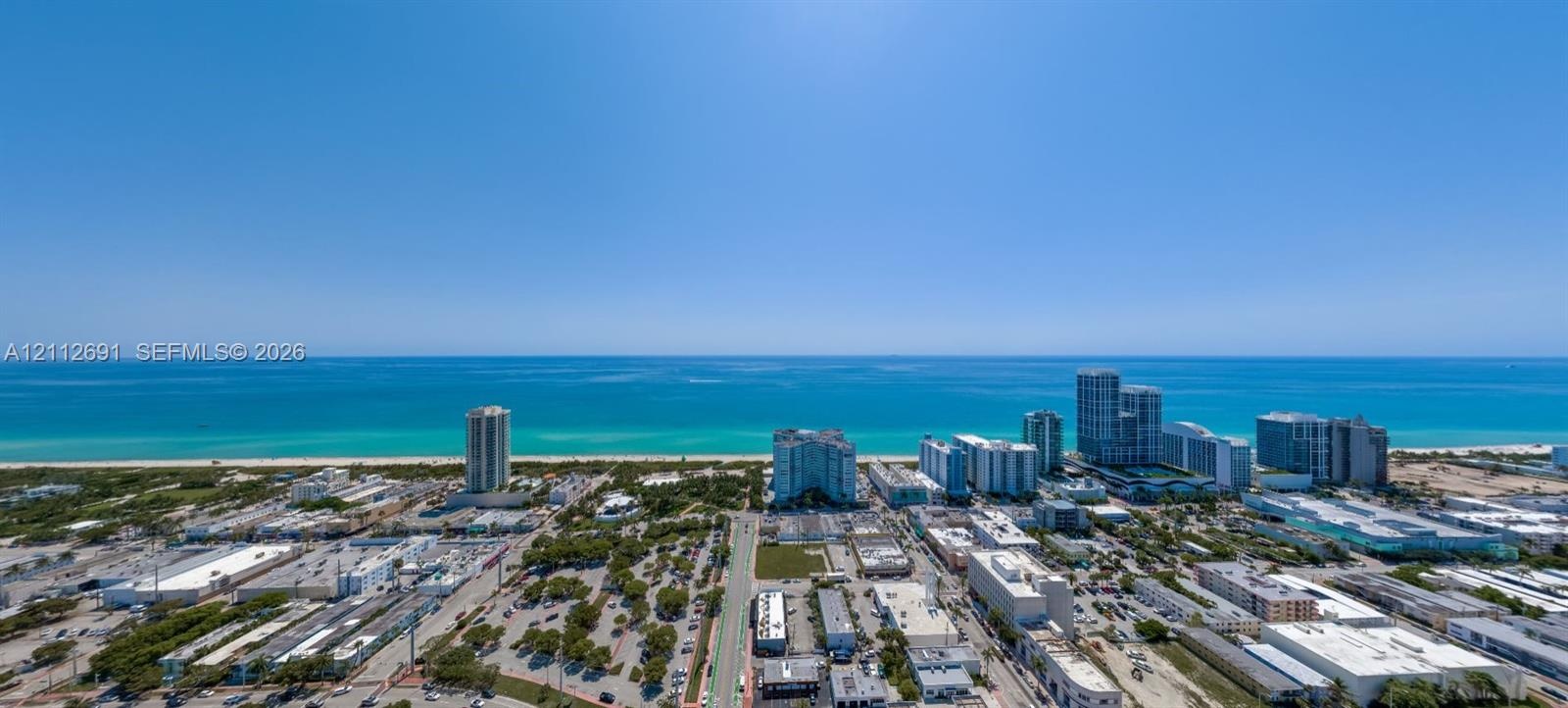 Aerial perspective showcasing a coastal cityscape with direct ocean frontage and expansive horizon