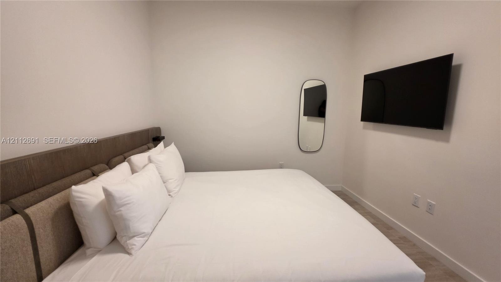 Neutral interior space featuring wood-finish flooring and wall-mounted electrical outlets
