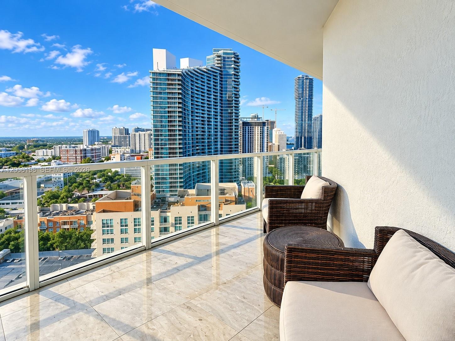 Private covered balcony featuring polished stone flooring and a glass panel railing system overlooking the cityscape