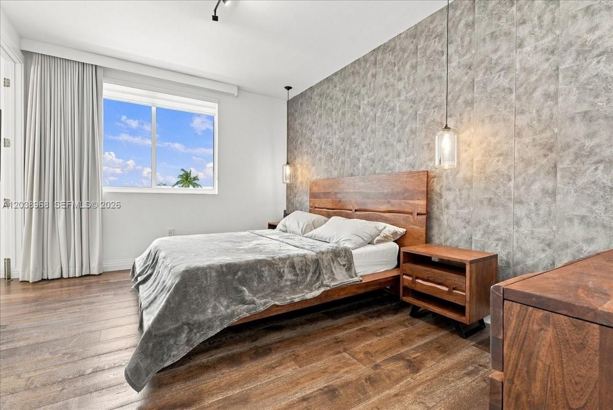 Textured accent wall, wood-finish flooring, and dual glass pendant light fixtures