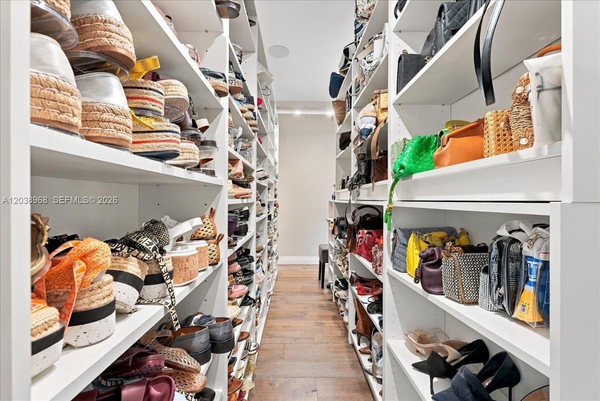 Custom floor-to-ceiling shelving with modular storage, built-in recessed ceiling lighting, and wide-plank wood-finish flooring