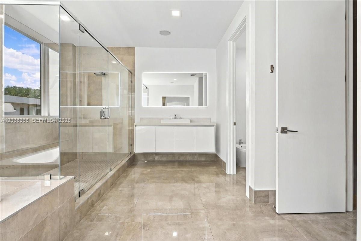Bathroom featuring a large glass-enclosed walk-in shower, floating vanity with an integrated sink, rectangular illuminated wall mirror, and large-form